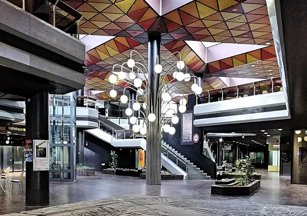Öffentlich zugängliches, zentrales Foyer mit Galerien und dreieckigen Shed-Oberlichtern. Der markante Leuchtenbaum unterstreicht das Konzept des öffentlichen Stadtraums. (Bild: Valerie Gerards)